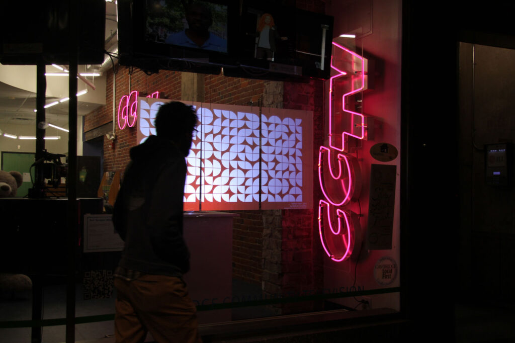 projection on plexiglass screen in window, person walking by