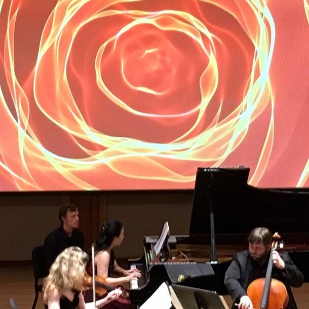 musicians playing in front of large colorful projection