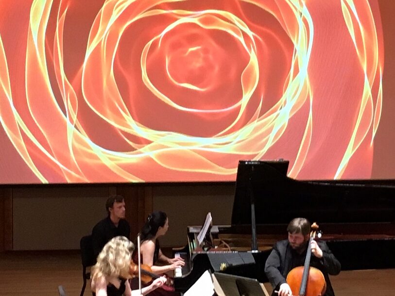 musicians playing in front of large colorful projection